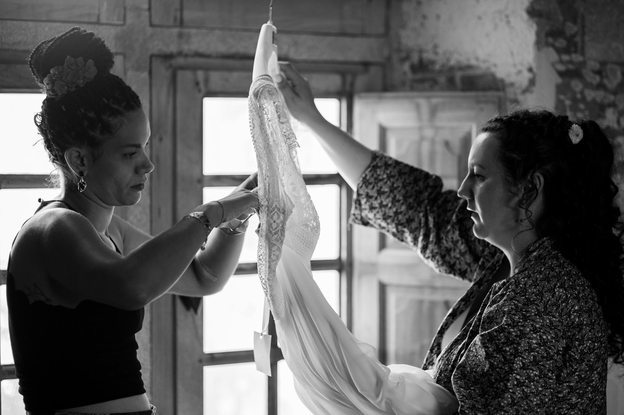 Mariée aidée pour l'habillage, voile déployé, en noir et blanc
