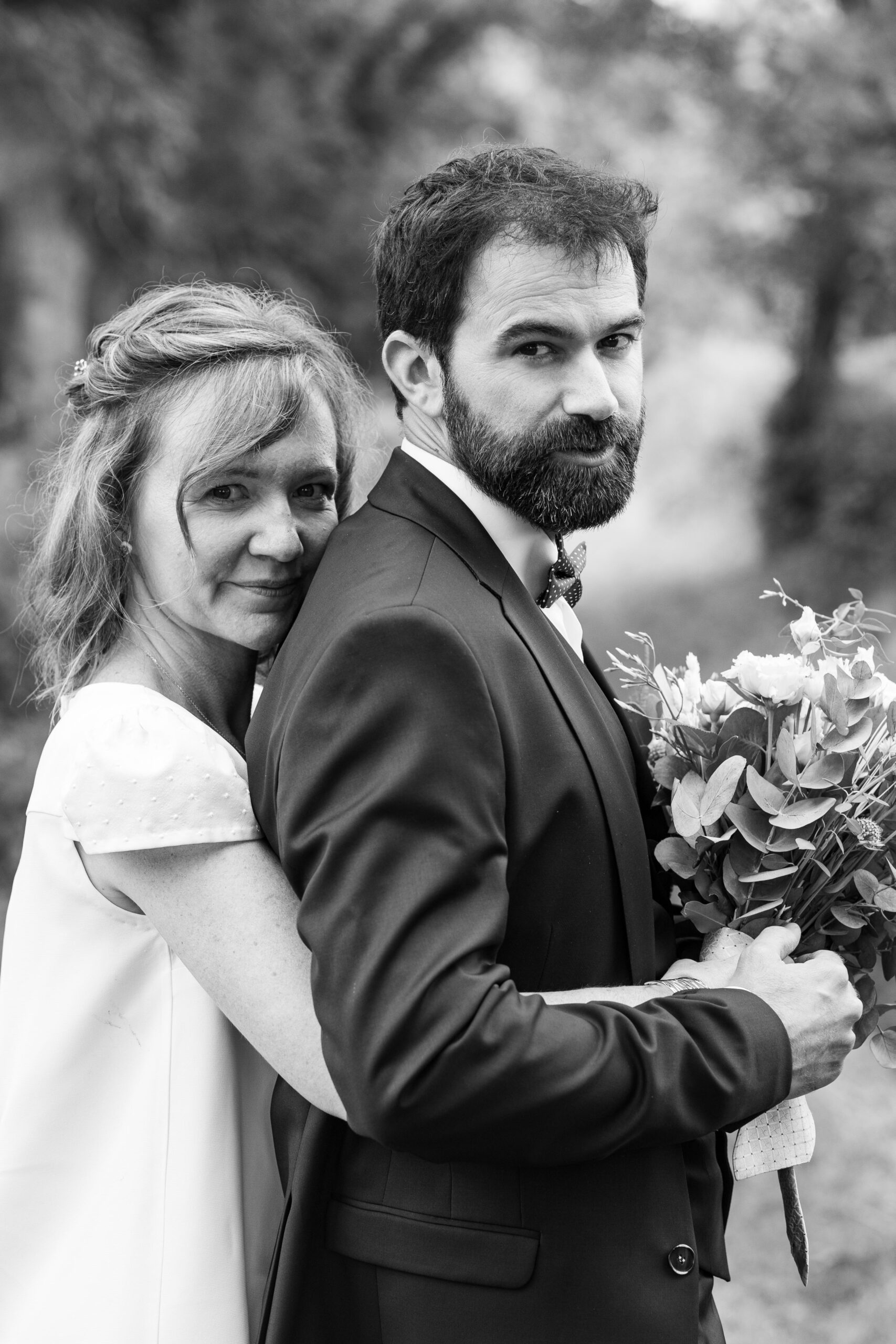 Mariés enlacés tenant le bouquet, portrait en noir et blanc